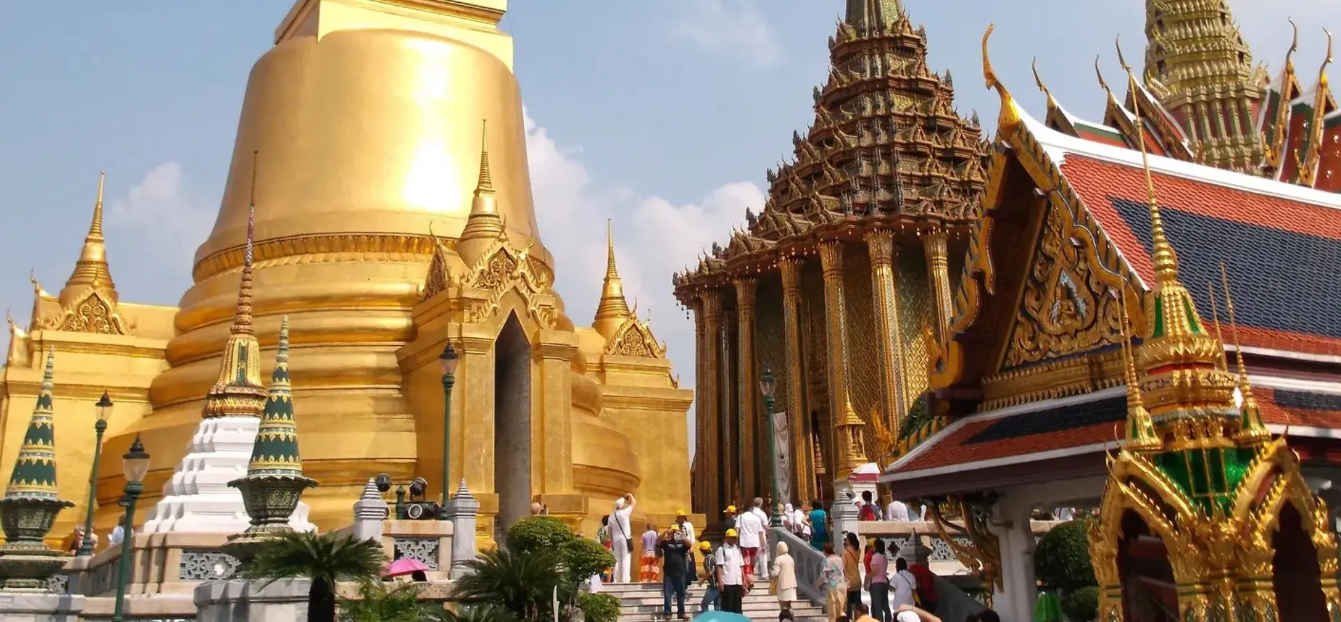 A group of people walking around in front of some gold colored buildings.