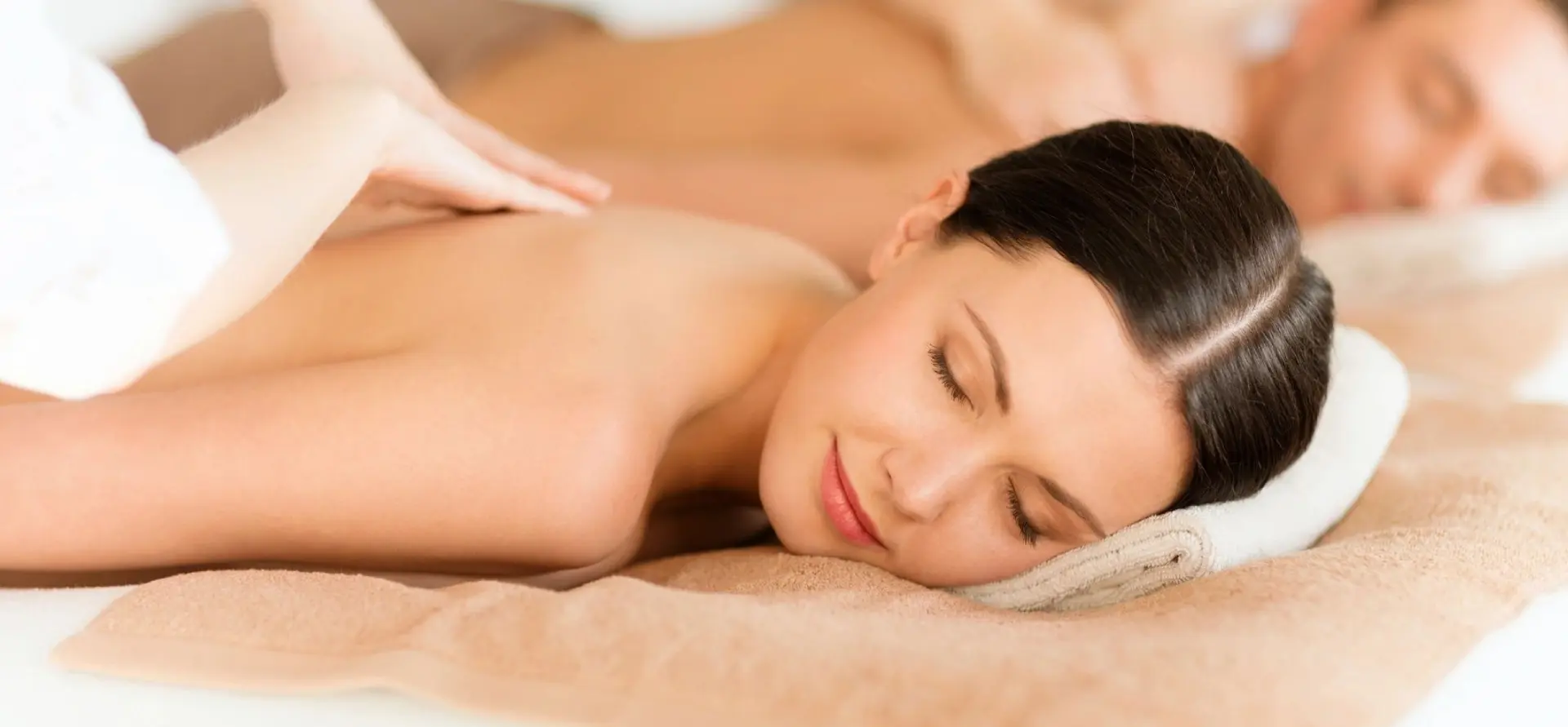 A woman laying down on her stomach with a hand touching the back of her head.